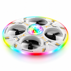 Low side view of the white RC UFO drone showing its protective rim, four guarded rotors, and color-changing LEDs.