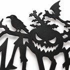 Macro of the laser-cut metal plaque: grinning pumpkin face, crow, bat and branch silhouettes