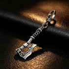 Macro photograph displaying the carved bearded blade edge, pitted forged textures, and oxidized shadows of the axe charm.