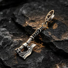 The antique axe keychain attached to a set of truck keys and remote fob on a rugged wooden work bench.