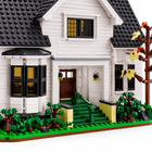 Close view of Bella House building-block manor porch with green steps, railings, brown door and black-framed windows.