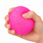 Hand gently compressing the hot-pink crunchy textured stress ball