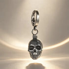 The silver skull keychain attached to a set of motorcycle ignition keys on a rugged leather jacket.