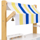 Detail of the market cart striped fabric awning, natural wooden frame and brass service bell.