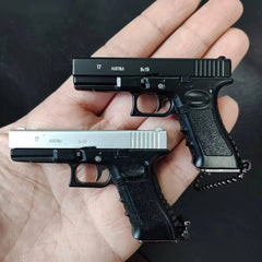 Two mini scale pistol model keychains in black and silver held in hand, collectible decoration