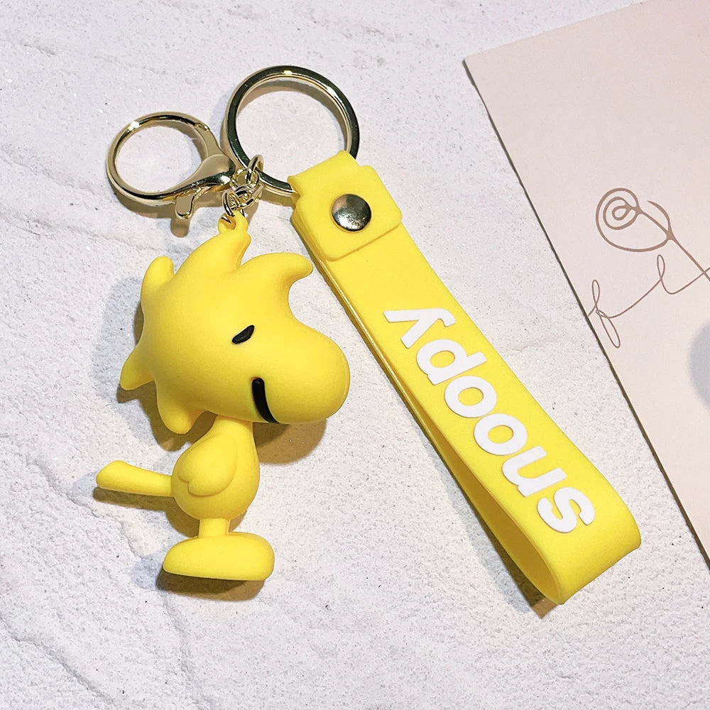 Yellow Woodstock Snoopy silicone keychain with matching yellow strap on a light background