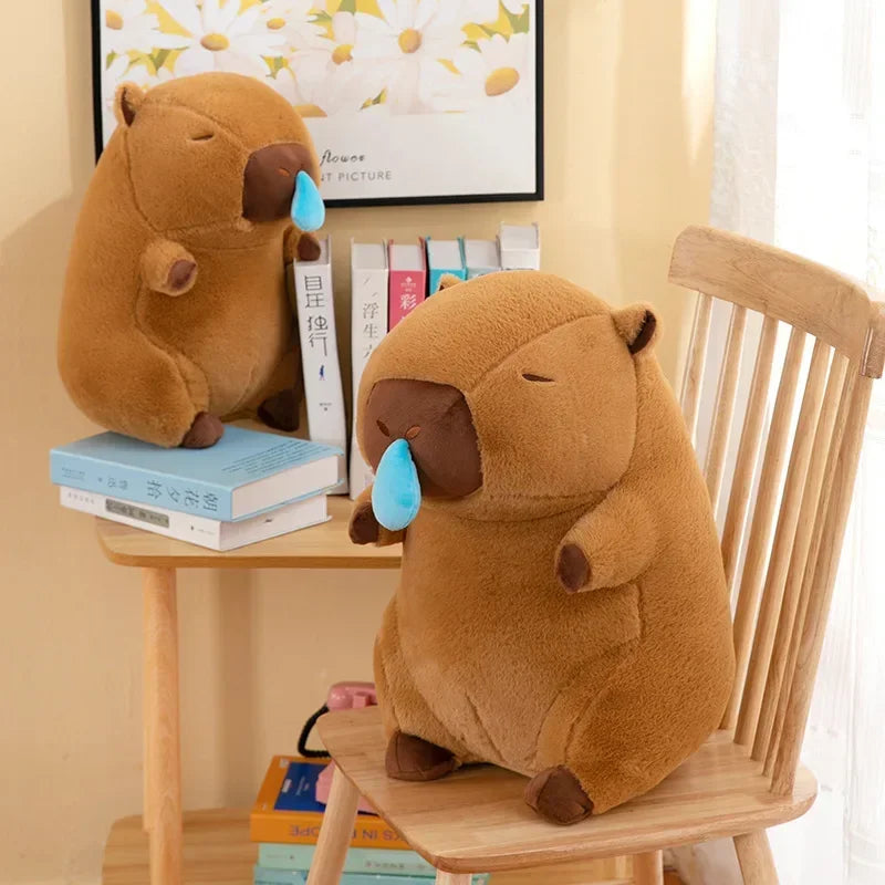 Two brown snot capybara plush toys sitting on a chair and stacked books in a cozy room