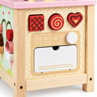 Close view of the wooden activity cube's pretend oven panel, red blocks, white knob and drop-down door.