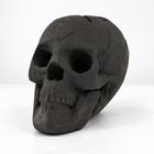 Black ceramic fire pit skull unlit, three-quarter view showing the matte charcoal texture and cracks