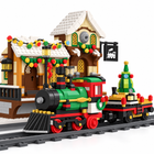 Close-up of green and red Christmas steam locomotive and tree wagon in front of the brick station - Toylvia