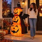 The 5-foot glowing three-tier pumpkin bat-wing display beside an adult on a porch; accurate 150 cm scale, no hands visible.