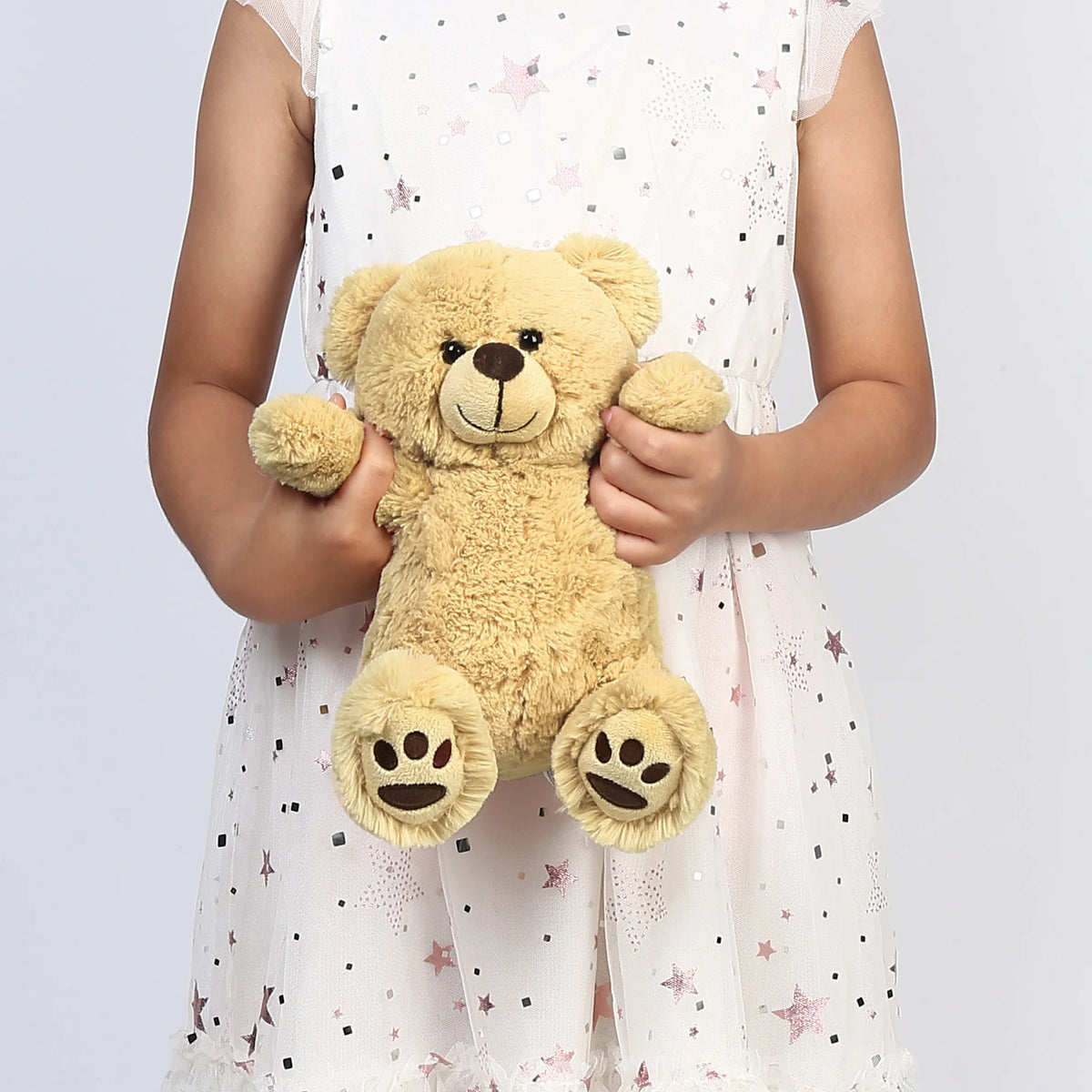 Child holding a teddy bear against a light purple background