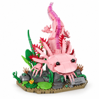 Pink brick-built axolotl model with frilled gills on a mossy base with reeds and lily pads