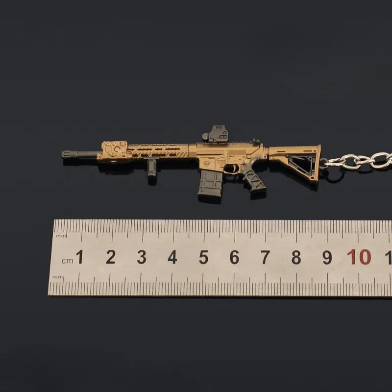Mini M110 gold and black rifle keychain placed next to a ruler showing 9 cm length on a dark background