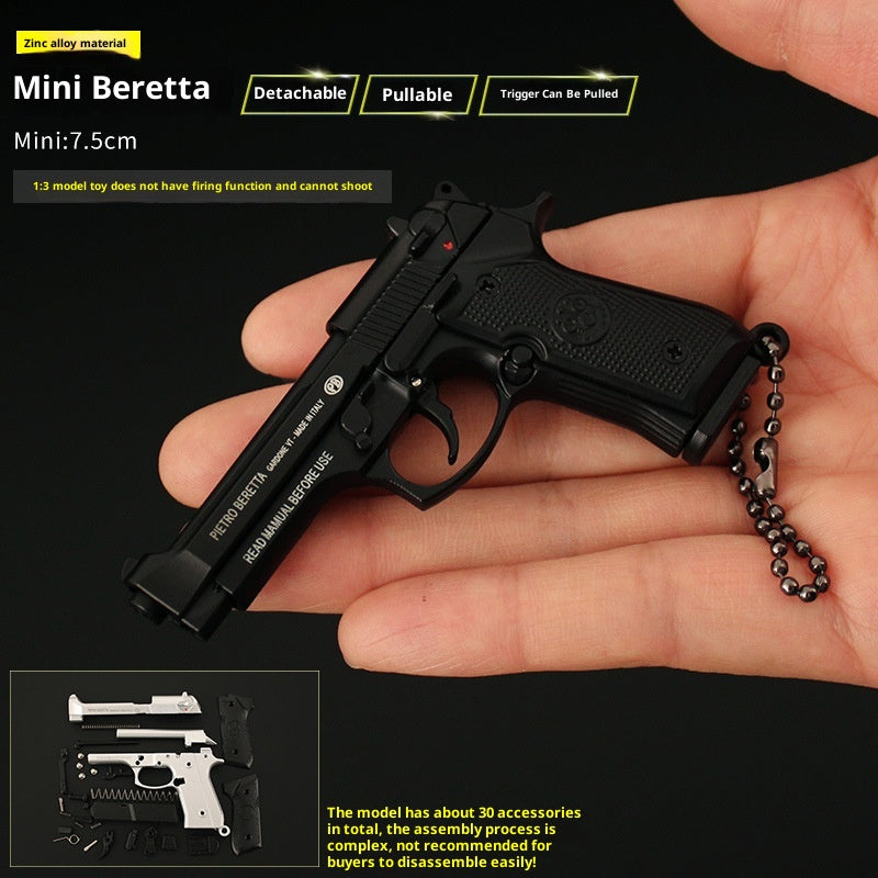 Miniature black Beretta gun model held in a hand with product details on a black background.