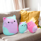 Three colorful cat-shaped cushions on a sofa with a yellow pillow.