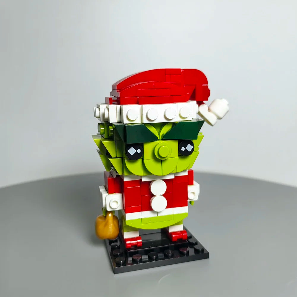 Christmas Green Monster MOC building blocks figure wearing Santa hat, displayed on gray surface, festive DIY model by Toylvia