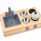 Close view of mud kitchen sink, red and blue taps, steel mixing bowls and gray cooking pot