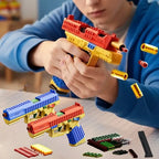 Child playing with a toy gun made of interlocking bricks on a table.