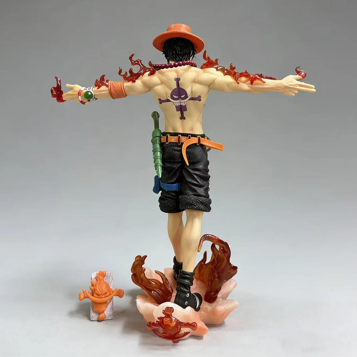 Fire Fist Ace action figure back view displaying back tattoo, flame arm effects, shorts, and accessory details on gray background