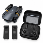 Overhead view of the folded drone, carrying case, remote and two batteries