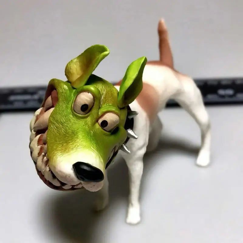 Funny dog figurine with a green cartoon mask, wide eyes, and spiked collar on a studio background