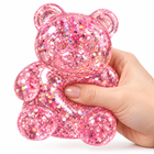 Hand gently compressing the translucent pink glitter bear squishy