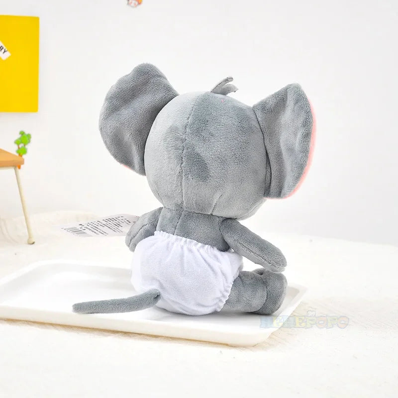 Gray plush elephant toy on a white surface with a yellow wall in the background