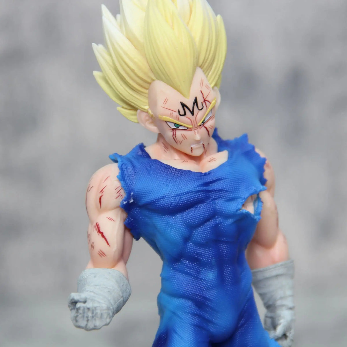 Majin Vegeta action figure upper body close-up showing spiky yellow hair, muscular detail, and battle damage on gray background