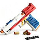 A toy construction-style pistol made from interlocking building blocks, shown on a clean white background with two toy bullets and a small black block piece nearby. The pistol is primarily white, red, and blue with small yellow and orange accents.