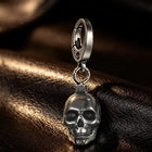 Macro photograph displaying the deep-set eye orbits, sculpted teeth, and polished silver cheekbones of the skull pendant.