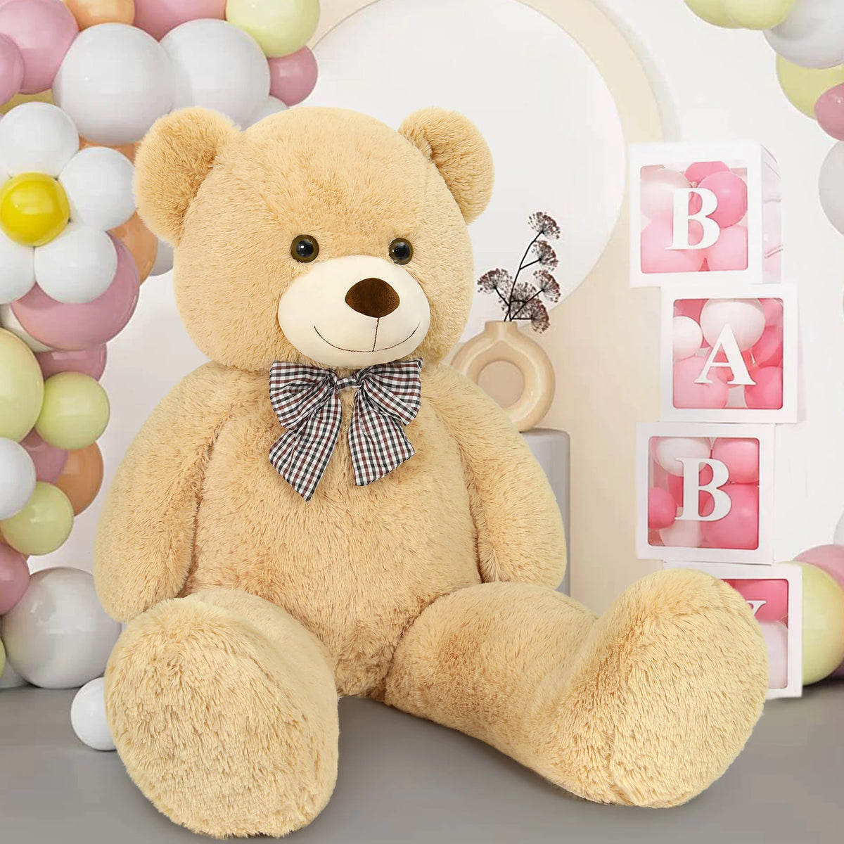 Large teddy bear with a bow tie in front of a 'BABY' sign and balloons.