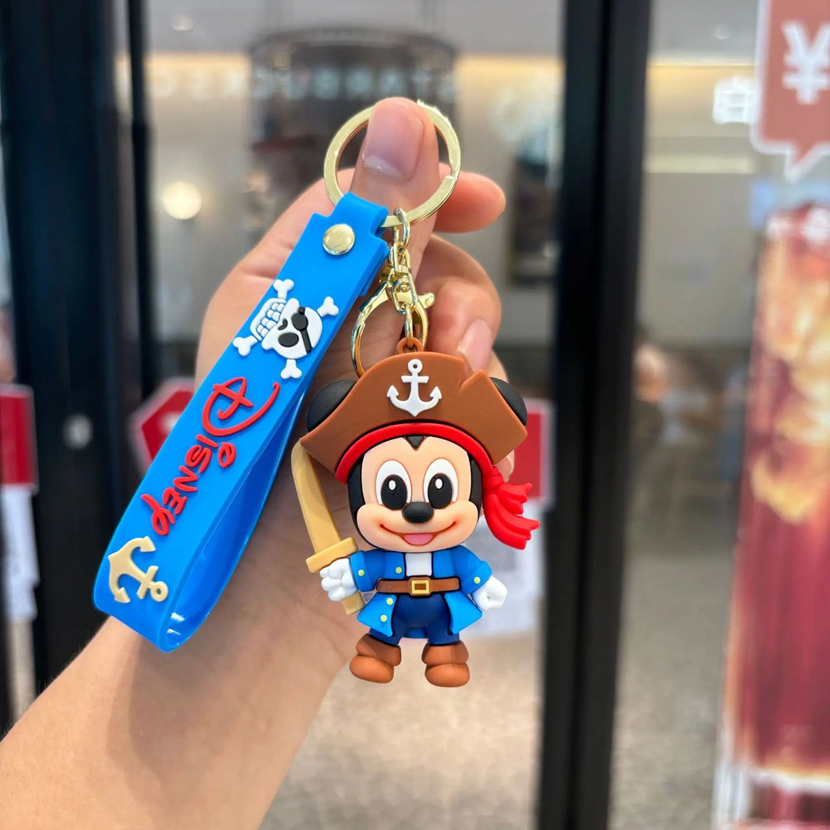 Pirate mouse cartoon PVC keychain with blue wrist strap, held in hand