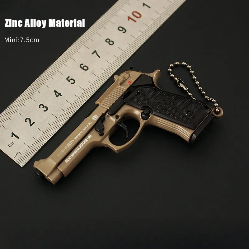 Pistol-shaped keychain with chain on a ruler for scale, on a dark background