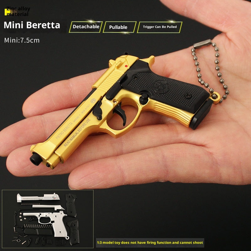 Gold and black Mini Beretta keychain held in a hand with product details on a dark background.