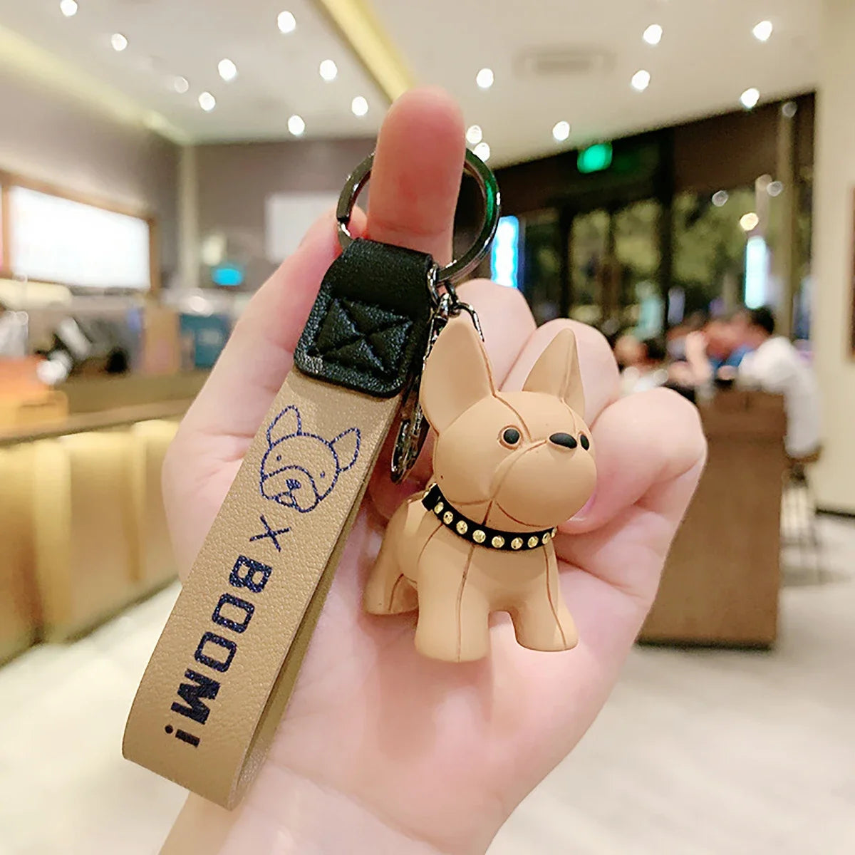 Brown punk French bulldog keychain with PU leather strap held in hand, cute dog charm for keys or bags