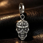 Macro photograph displaying the deep hollowed eye orbits, defined nasal aperture, and sculpted dental arches of the silver skull fob.