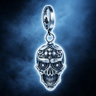 Adult hand holding the solid silver skull key fob in an open palm to display scale, proportions, and metallic shine.