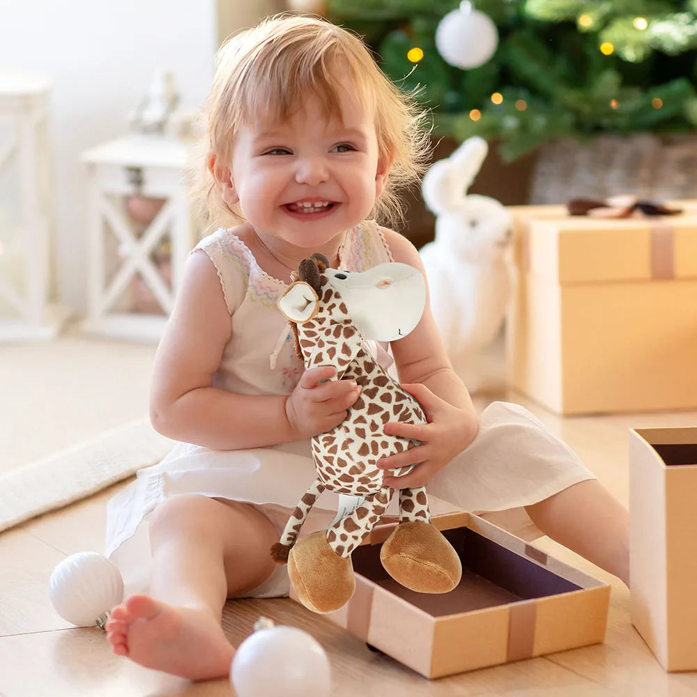 Child holding a giraffe toy in a decorated room with Christmas decorations.