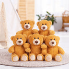 Five yellow teddy bears stacked on a textured surface with a blurred indoor background