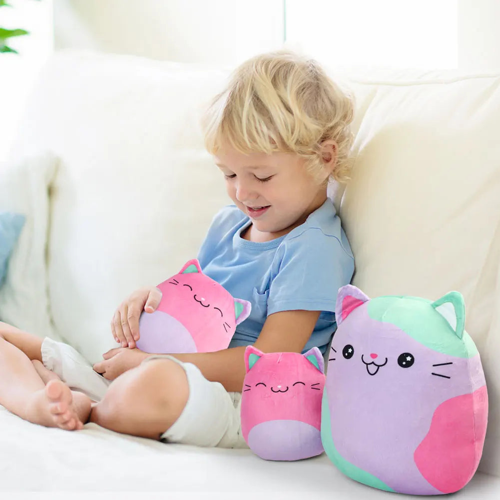 Child playing with colorful cat-shaped plush toys on a white couch.