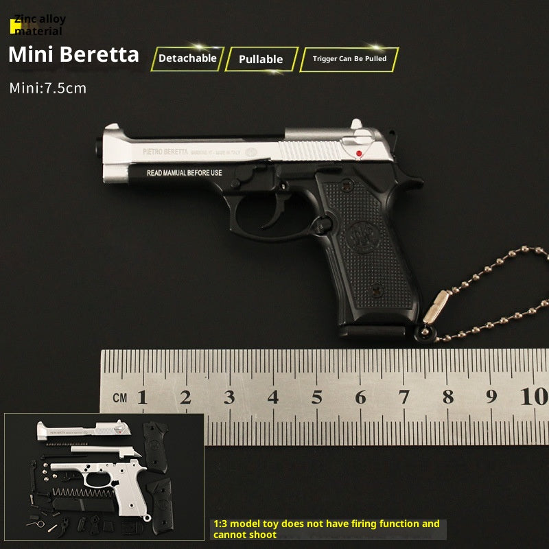 Miniature Beretta gun model with detachable pullable trigger on a black background, accompanied by a ruler for scale.