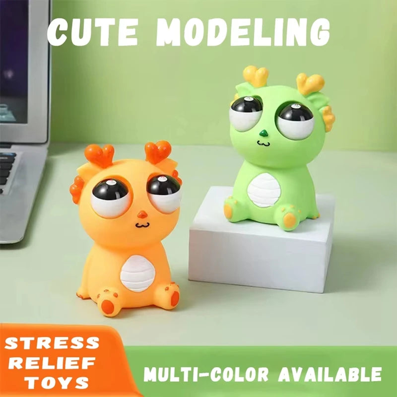 Cute pop-out eyes dragon stress relief squeeze toy in green and orange colors on desk background