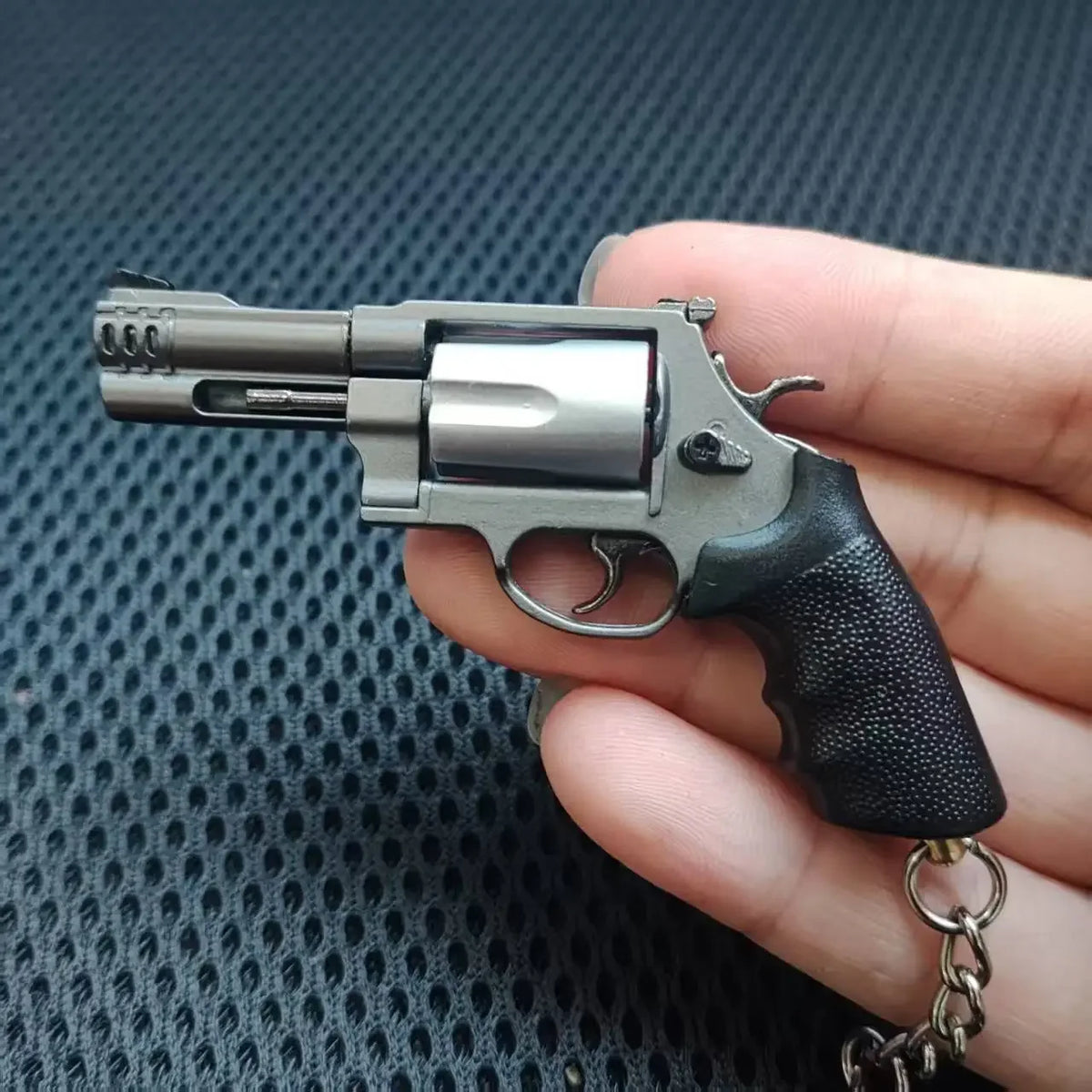Mini M500 revolver metal keychain collectible in silver finish held in hand