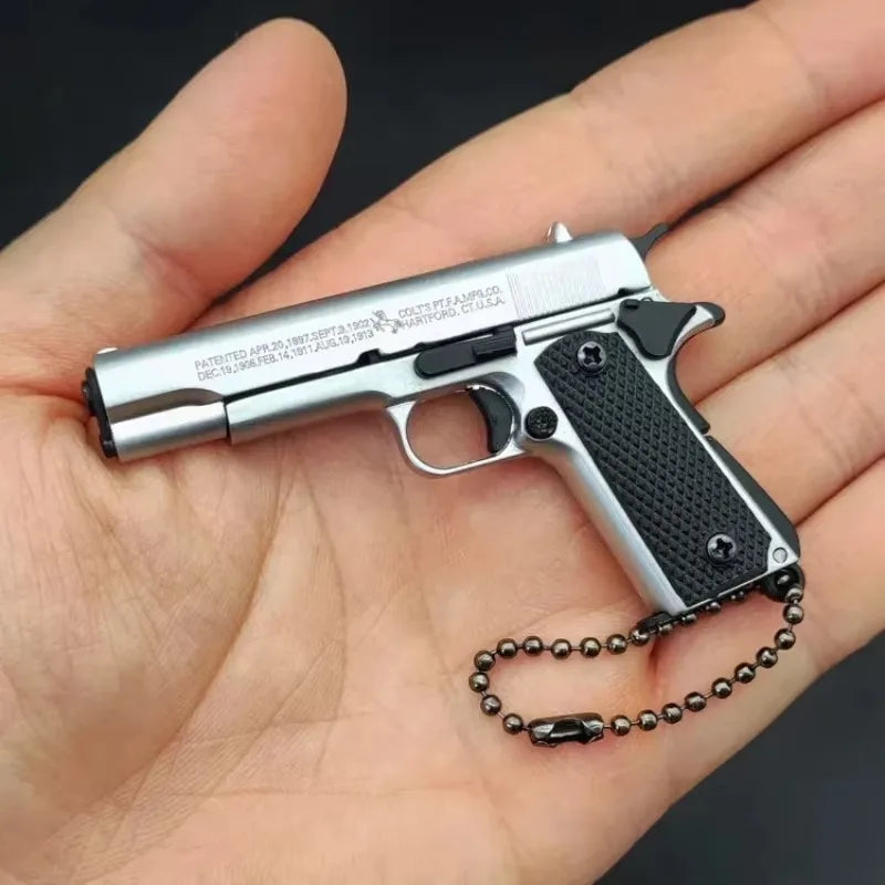 Silver classic mini scale pistol model keychain held in hand, decorative collectible keychain