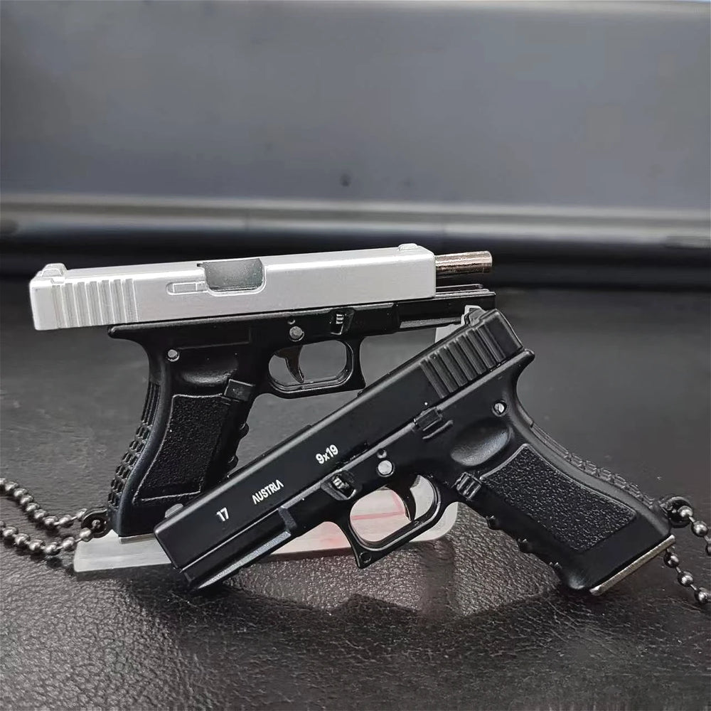 Stacked mini scale pistol model keychains on a dark background, metal collectible models