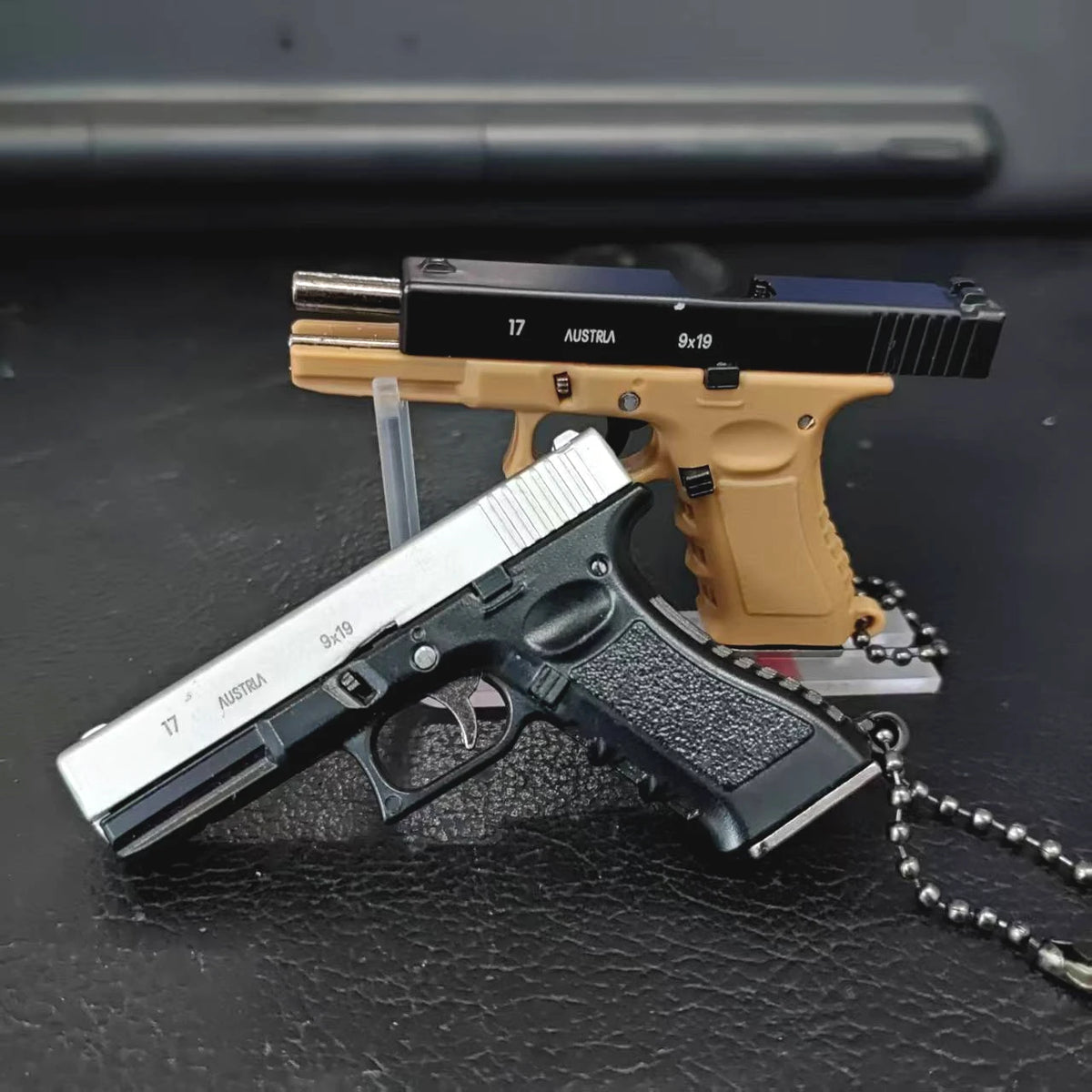 Mini scale pistol model keychains displayed on a dark surface, decorative collectible models