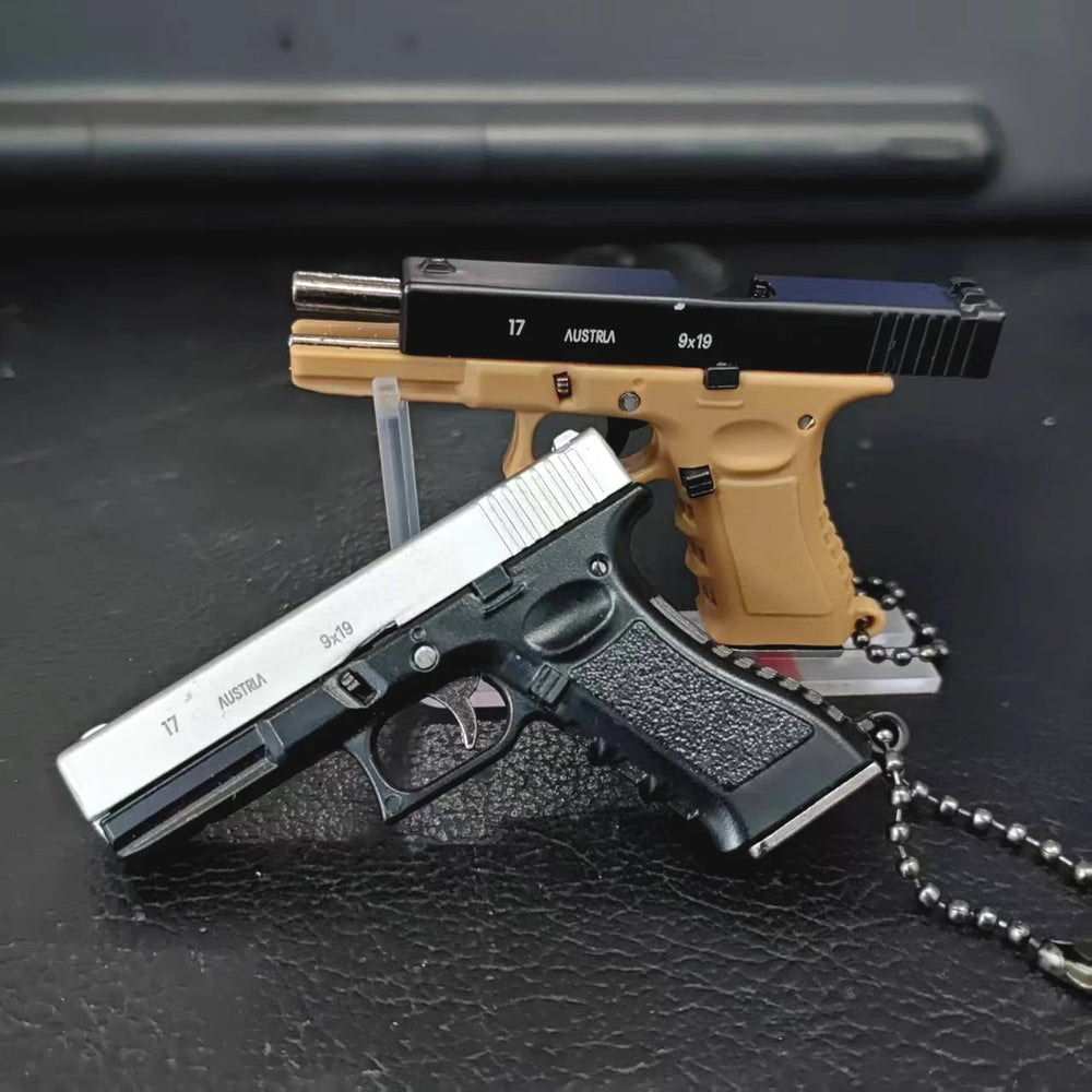 Mini scale pistol model keychains displayed on a dark surface, decorative collectible models