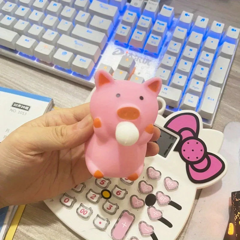 Cute pink pig squishy fidget toy held at desk near keyboard and calculator, stress relief squeeze toy for work and study
