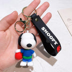 Snoopy keychain with black ‘Snoopy’ strap, held in a hand, featuring Snoopy in a blue outfit holding a red basketball on a white background